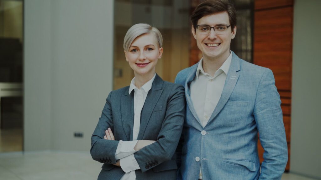 A man and woman in business attire smiling.